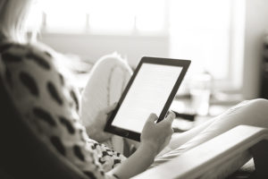 A woman sitting and reading something on a tablet.
